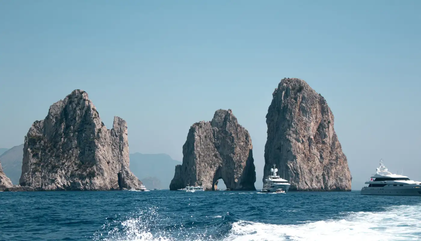 Les rochers des Faraglioni au large de Capri, avec des yachts sur la mer bleue