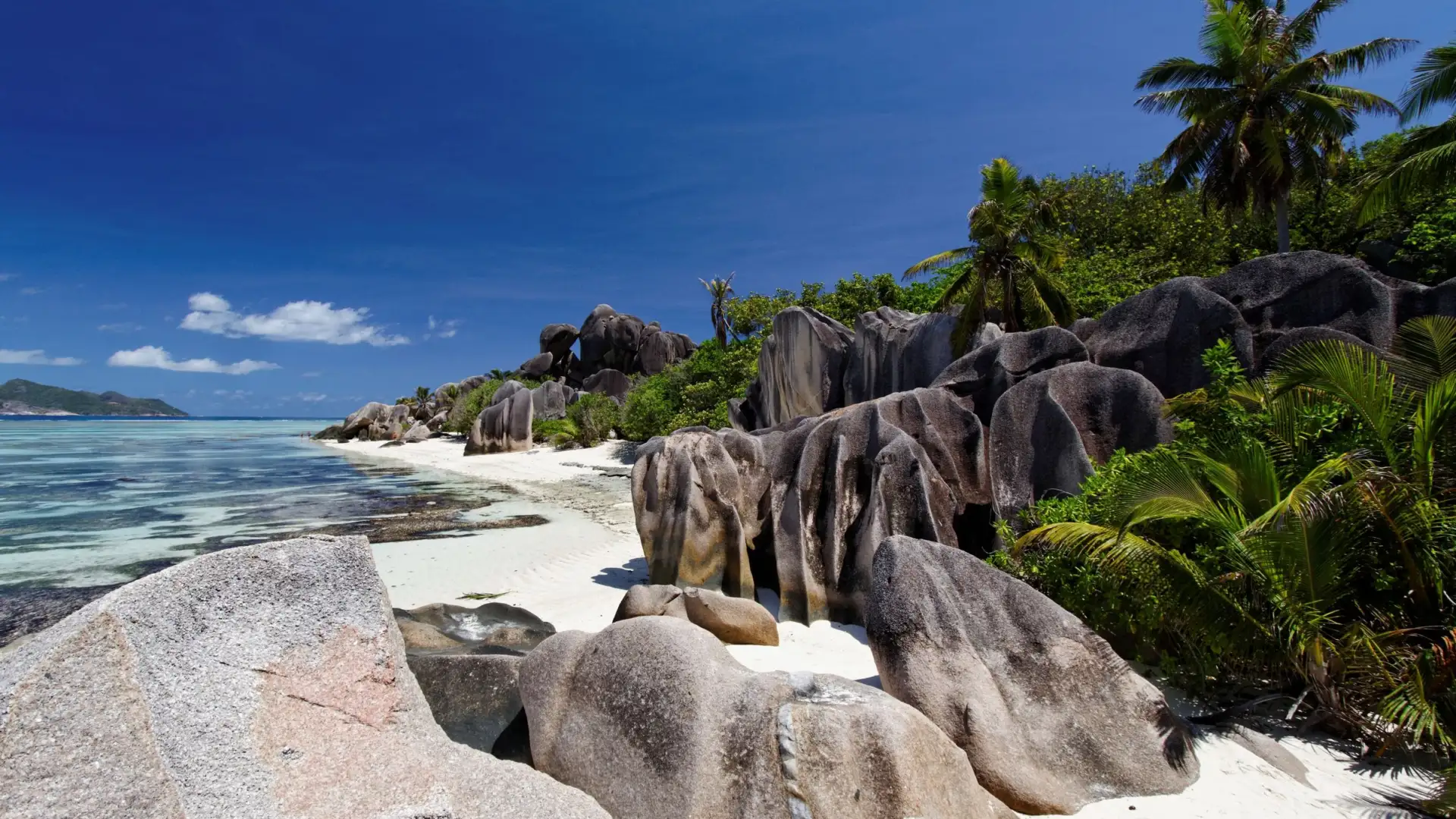 Rochers de granit et sable blanc sur une plage de La Digue aux Seychelles, cocotiers et lagon turquoise